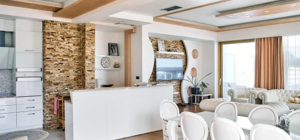 cuisine contemporaine avec table blanche, chaises capitonnées, murs en pierre